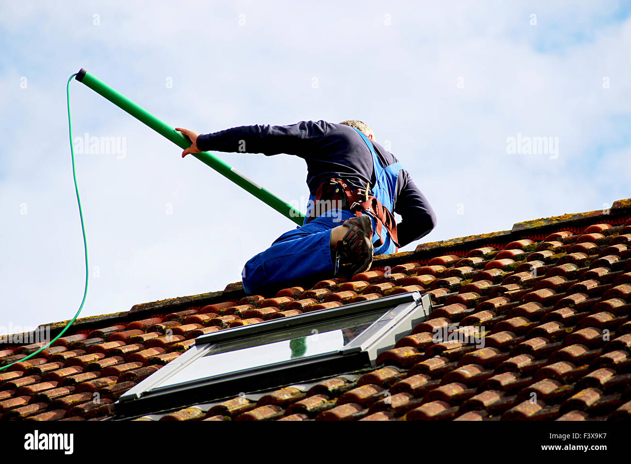 Sur le toit, d'un travailleur pour effacer la batterie solaire Banque D'Images