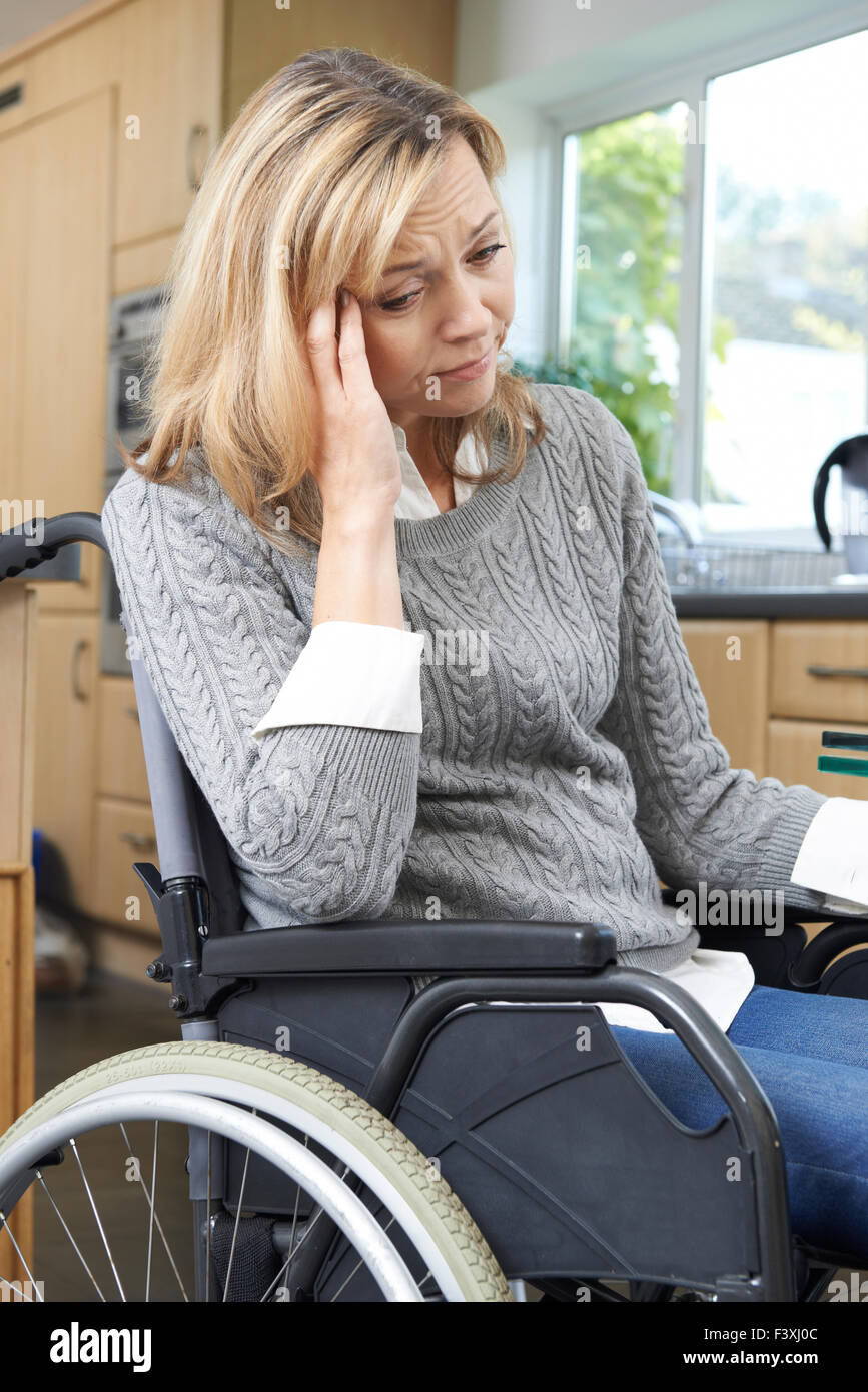 Déprimé Woman Sitting in Wheelchair At Home Banque D'Images