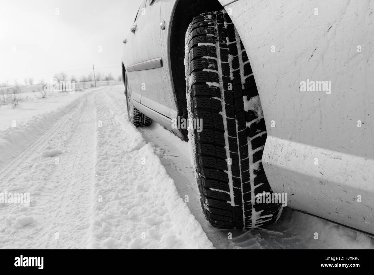 Close up d'un des pneus de voitures sur une route enneigée Banque D'Images