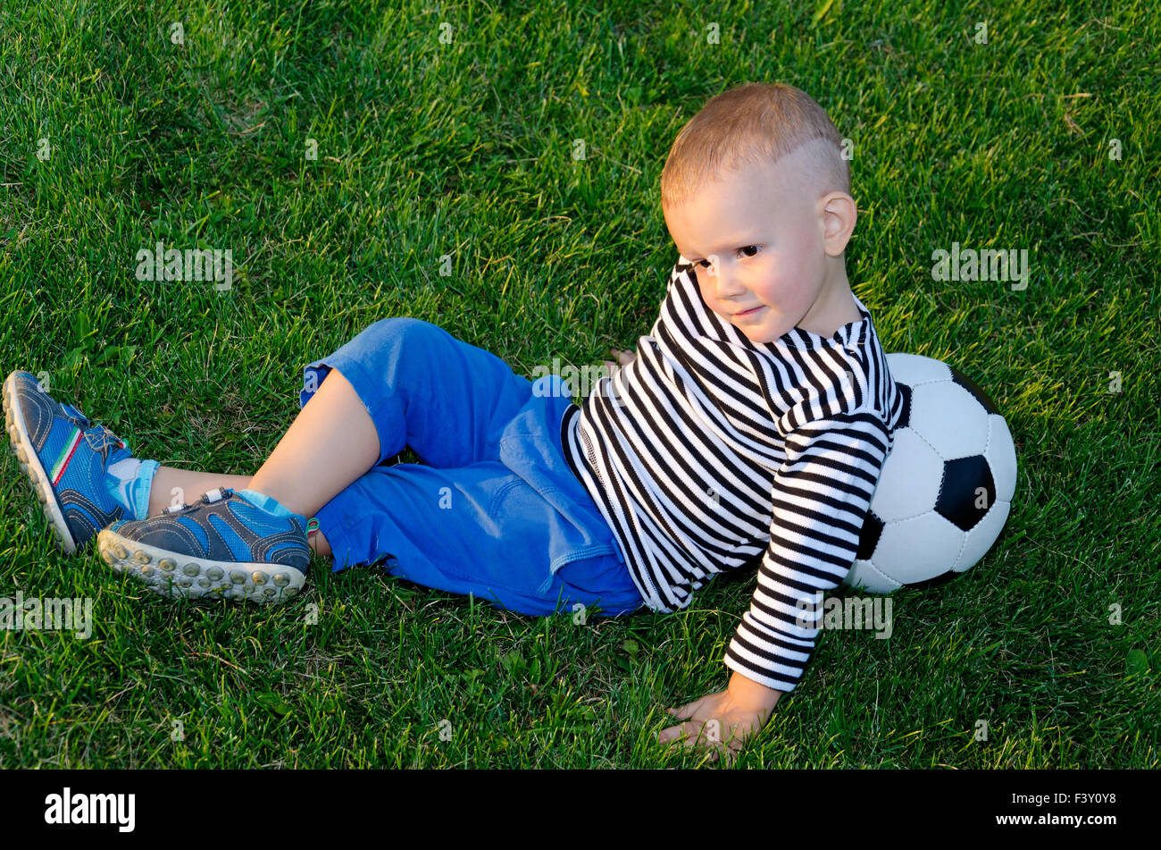Jeune allongé contre son ballon de soccer Banque D'Images