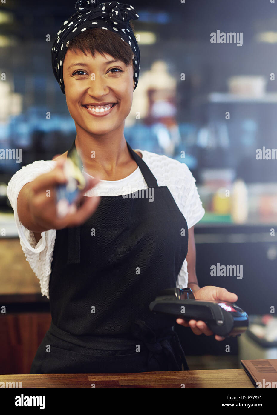 Pretty African American enthousiaste propriétaire de petite entreprise avec un joli sourire plein de vivacité rend le processus d'après une carte de crédit Banque D'Images