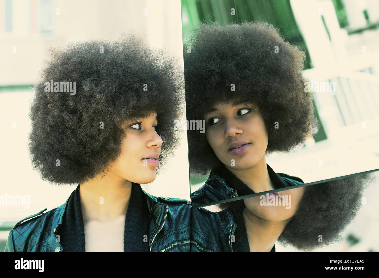Jeune femme à la recherche d'afro dans un miroir Banque D'Images