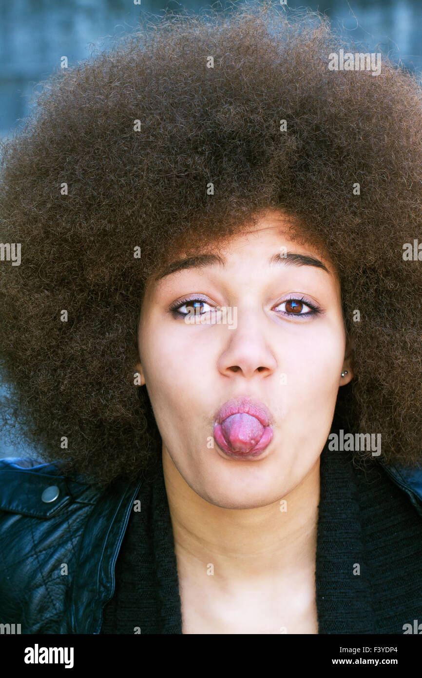Jeune femme afro sticking tongue out Banque D'Images