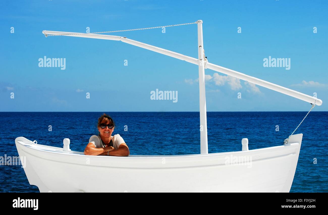 Woman smiling in un faux bateau blanc avec ciel bleu et mer bleue. Banque D'Images