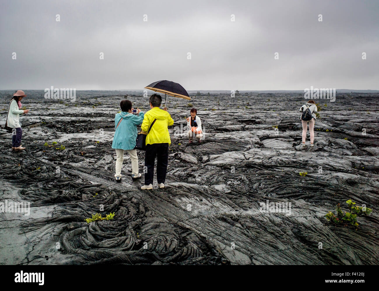 Les touristes japonais visiter un paysage pluvieux stérile de roche de lave champs, Hawai'i Volcanoes National Park, Big Island, Hawaii, USA Banque D'Images