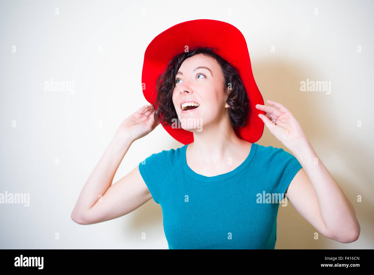 Jeune femme avec Red Hat et blue dress posing looking up Banque D'Images