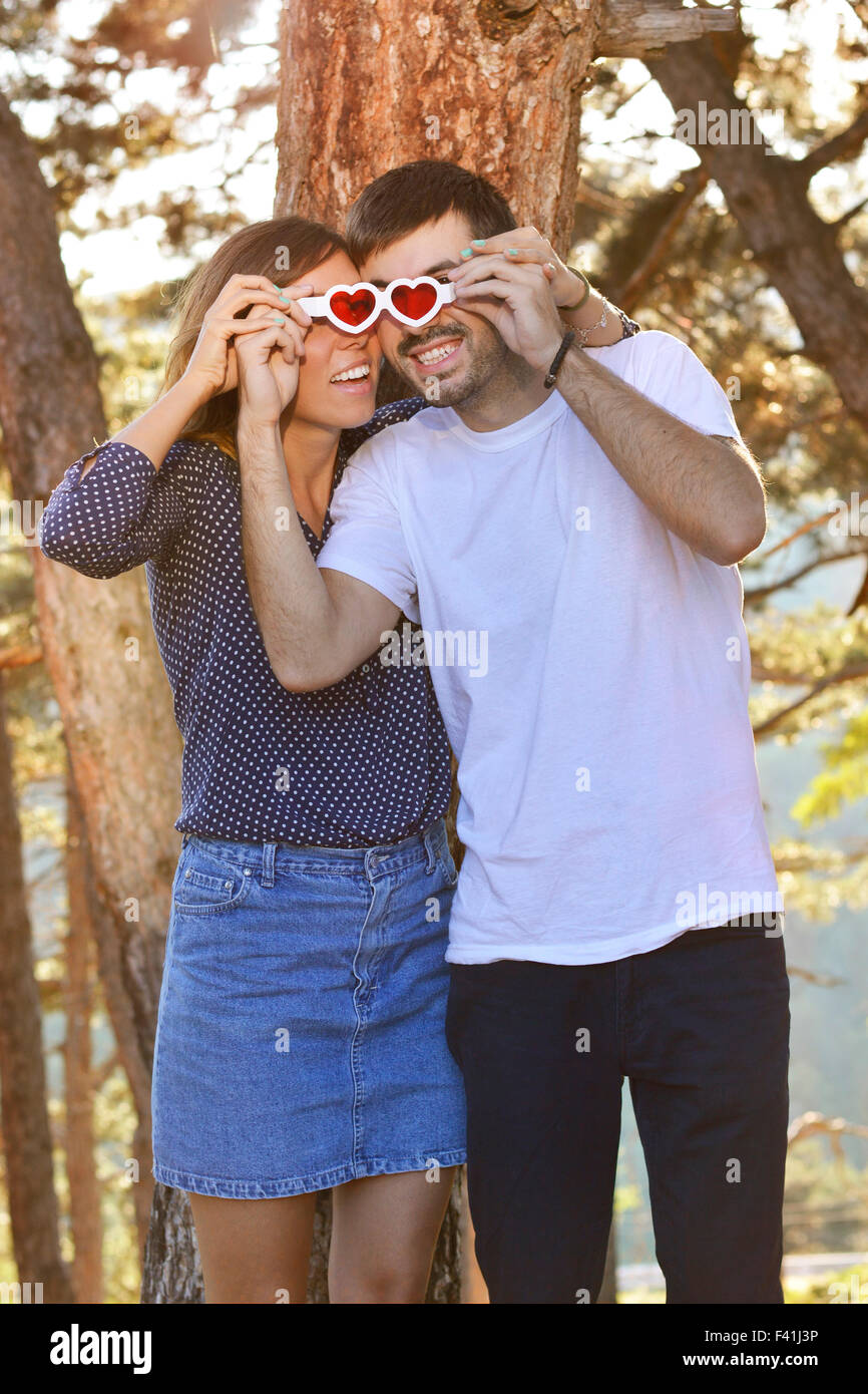 Couple heureux dans le parc à deux pas des lunettes en forme de coeur Banque D'Images