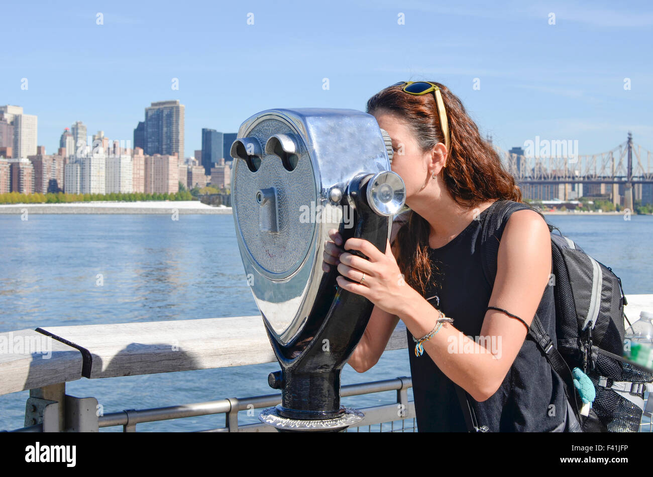 Girl looking thru jumelles public à la Manhattan vue. Reflets d'bincoulars on a sunny day Banque D'Images