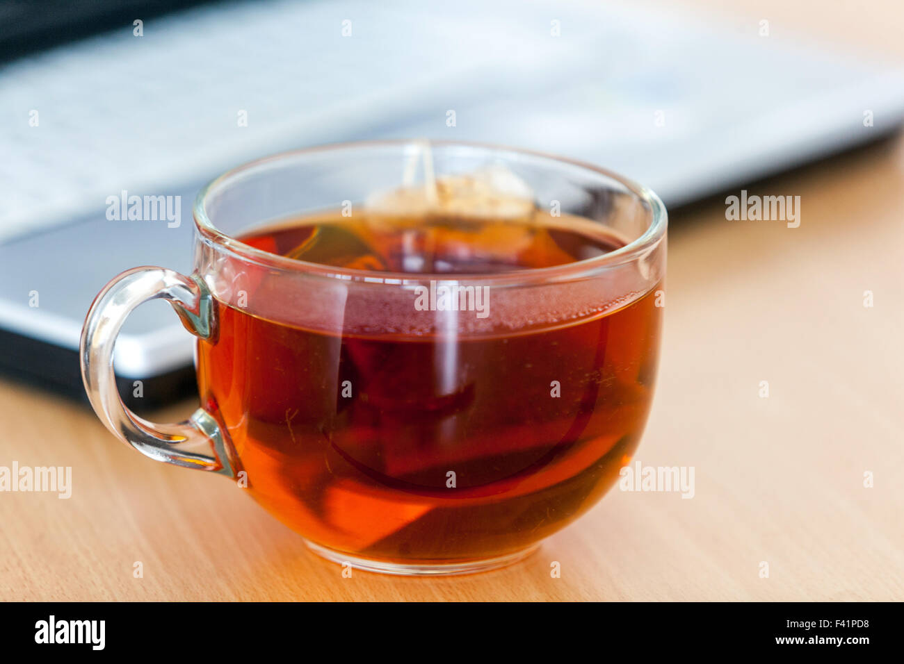 Une tasse de thé sur une table, ordinateur portable Banque D'Images