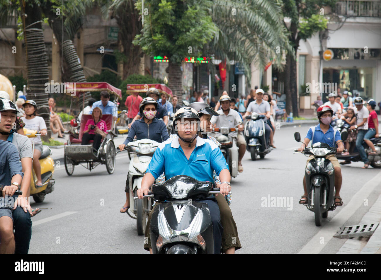 Sur les scooters vietnamiens équitation passé du lac Hoan Kiem de Hanoi, capitale du Vietnam. Les cavaliers avec Cyclo touristes équitation,Vietnam Banque D'Images