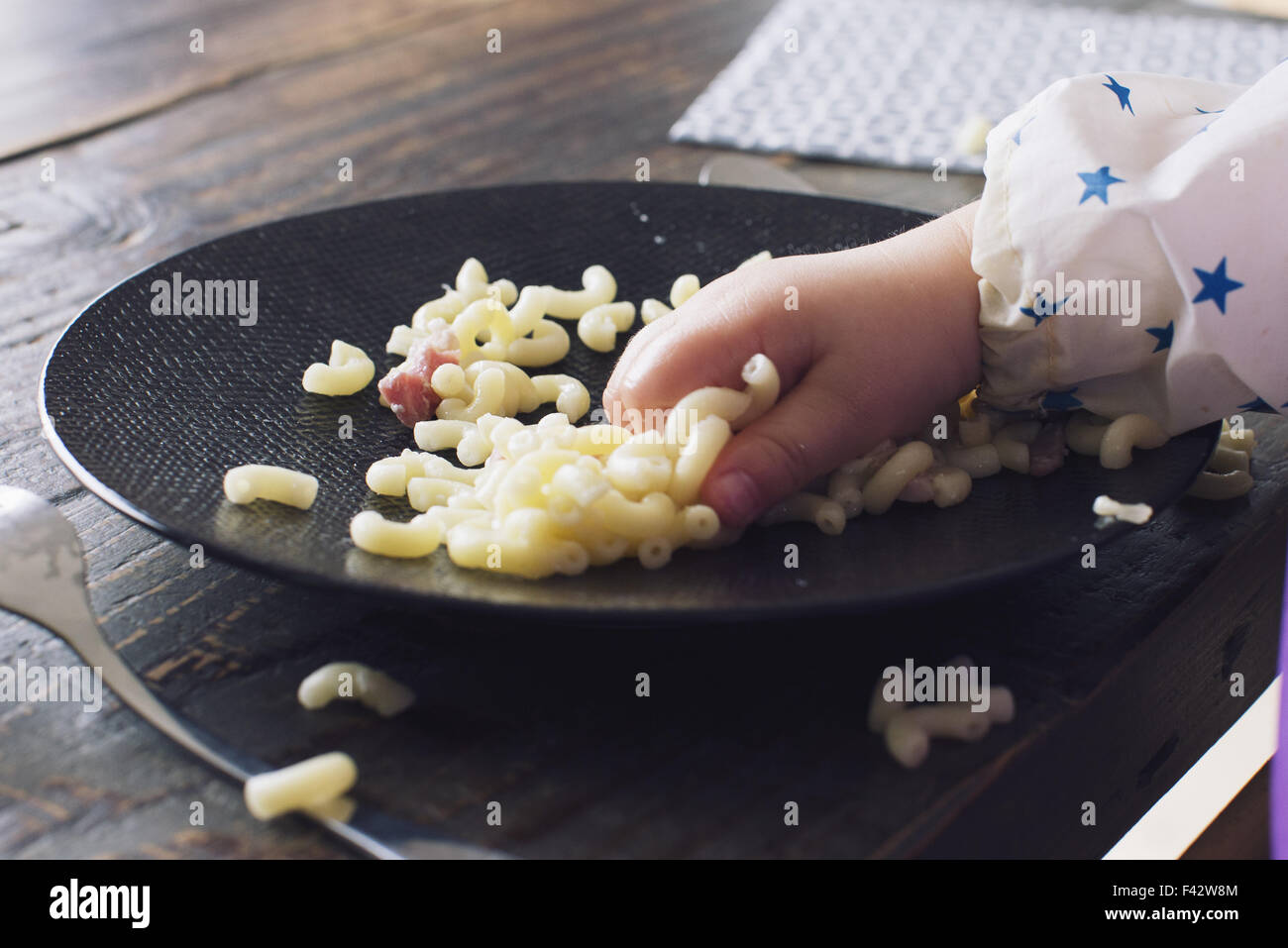 Enfant de manger des macaronis avec sa main, cropped Banque D'Images