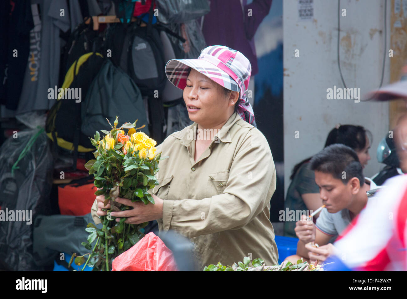 La rue vietnamienne vendeur de fleurs bouquet de fleurs remise à un acheteur, Hanoi, Vietnam Banque D'Images