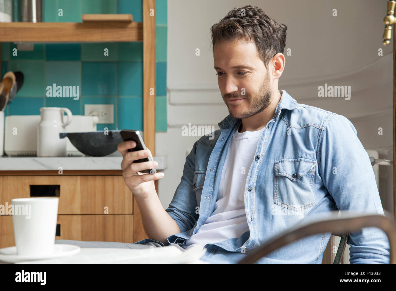 La lecture des nouvelles de l'homme sur smartphone pendant le petit-déjeuner Banque D'Images