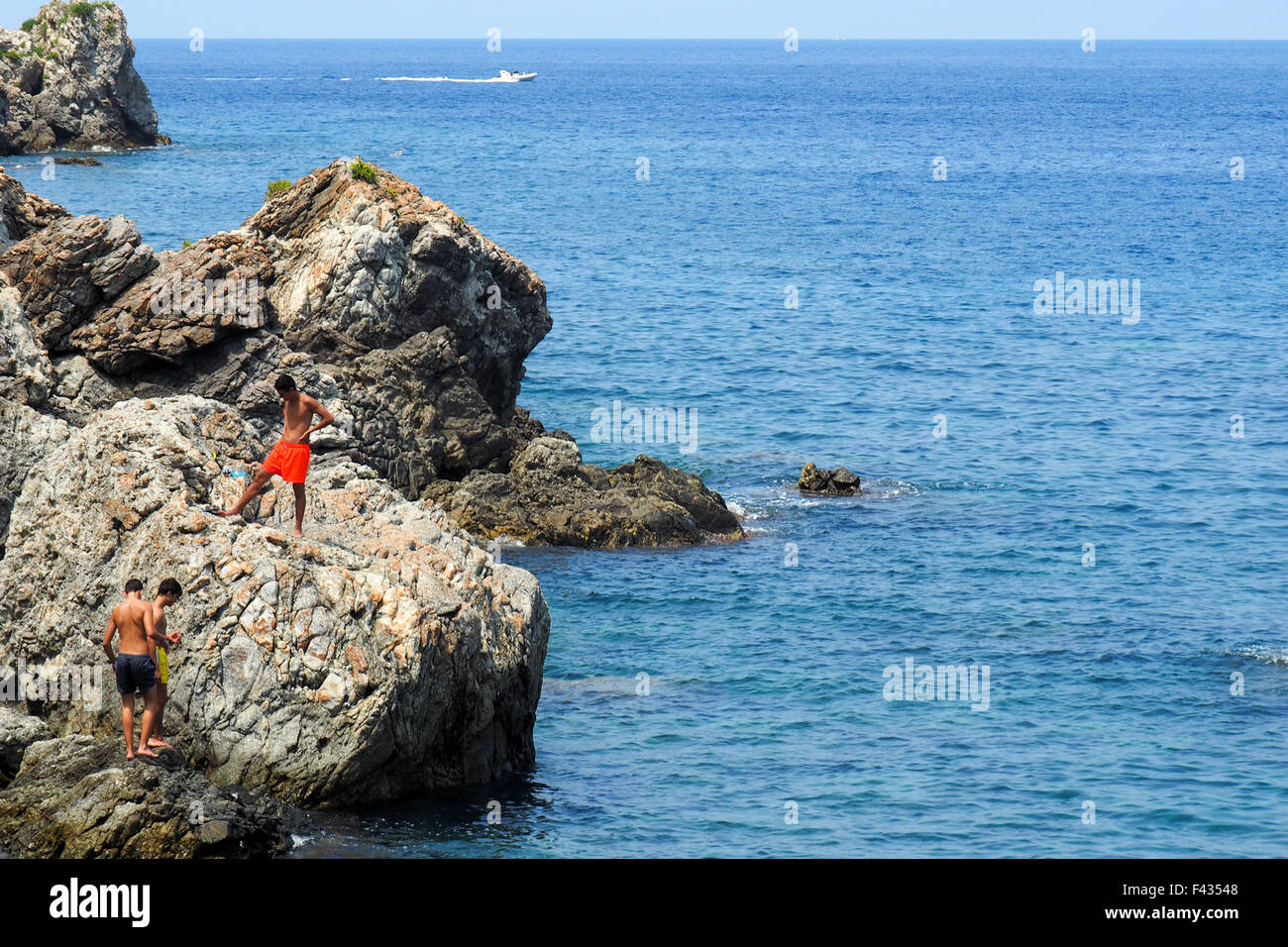 Trois adolescents sur les rochers sur la côte de Calabre, Italie. Banque D'Images