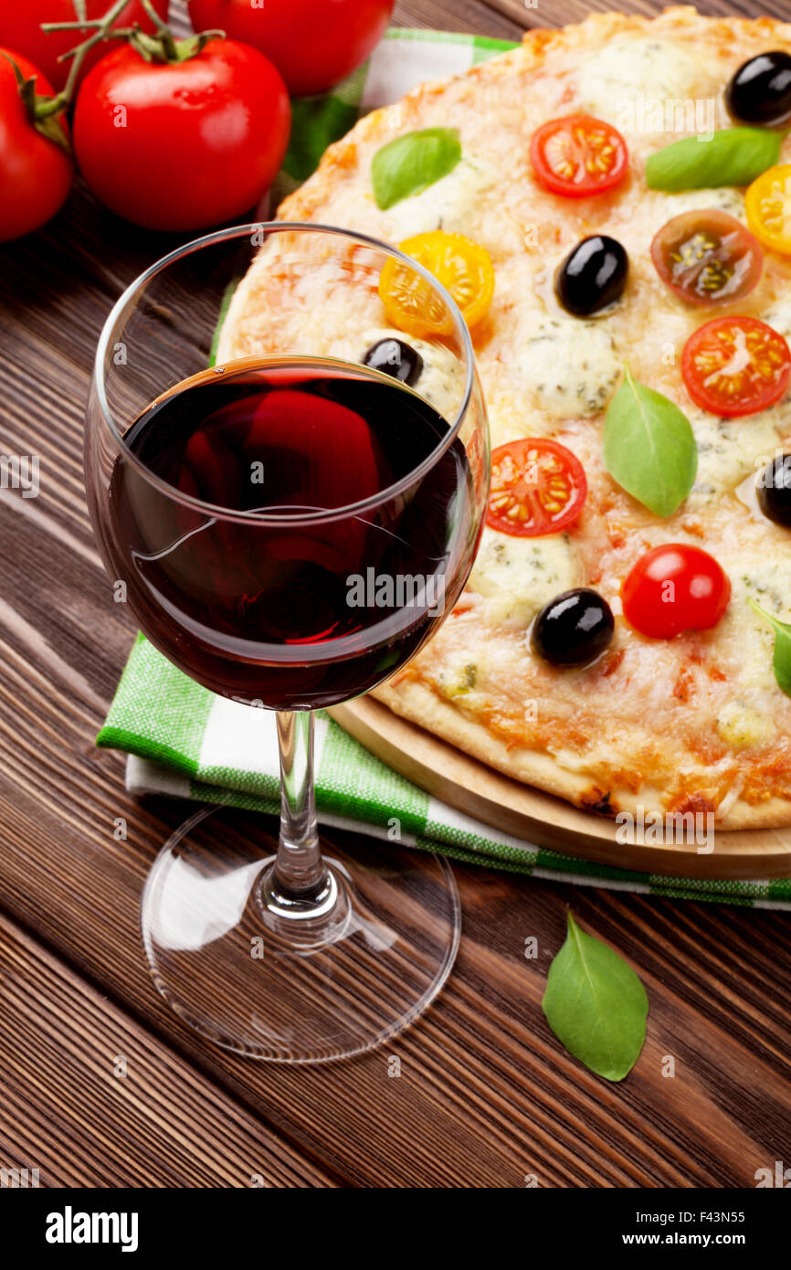 Verre de vin rouge et la pizza italienne avec fromage, tomates, olives et basilic Banque D'Images