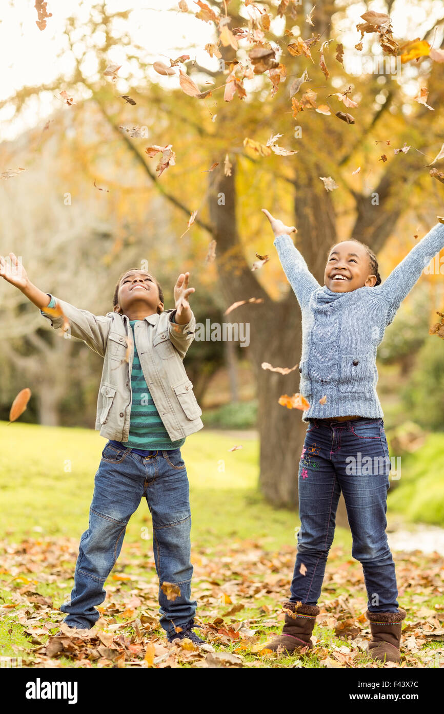 Portrait de jeunes enfants Jeter feuilles autour de Banque D'Images