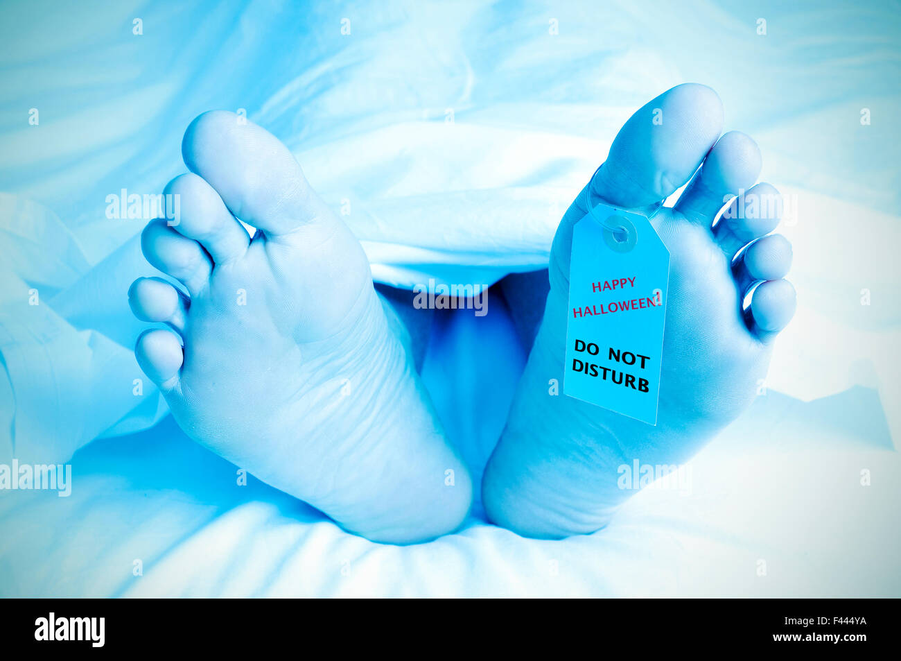 Gros plan des pieds d'un corps mort recouvert d'une feuille et à une étiquette attachée sur son gros orteil avec le texte happy Halloween, ne Banque D'Images