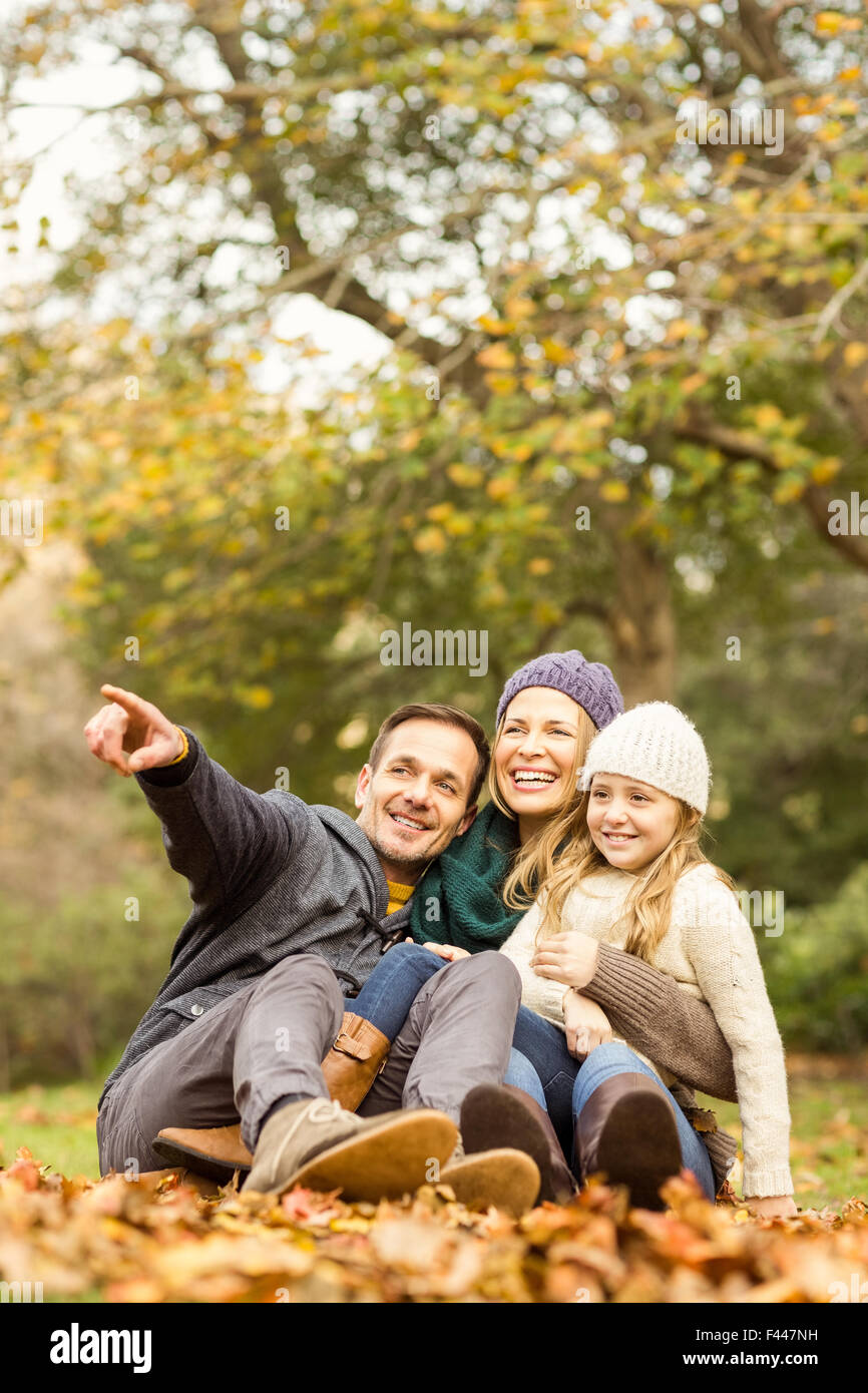 Smiling young family sitting dans les feuilles Banque D'Images