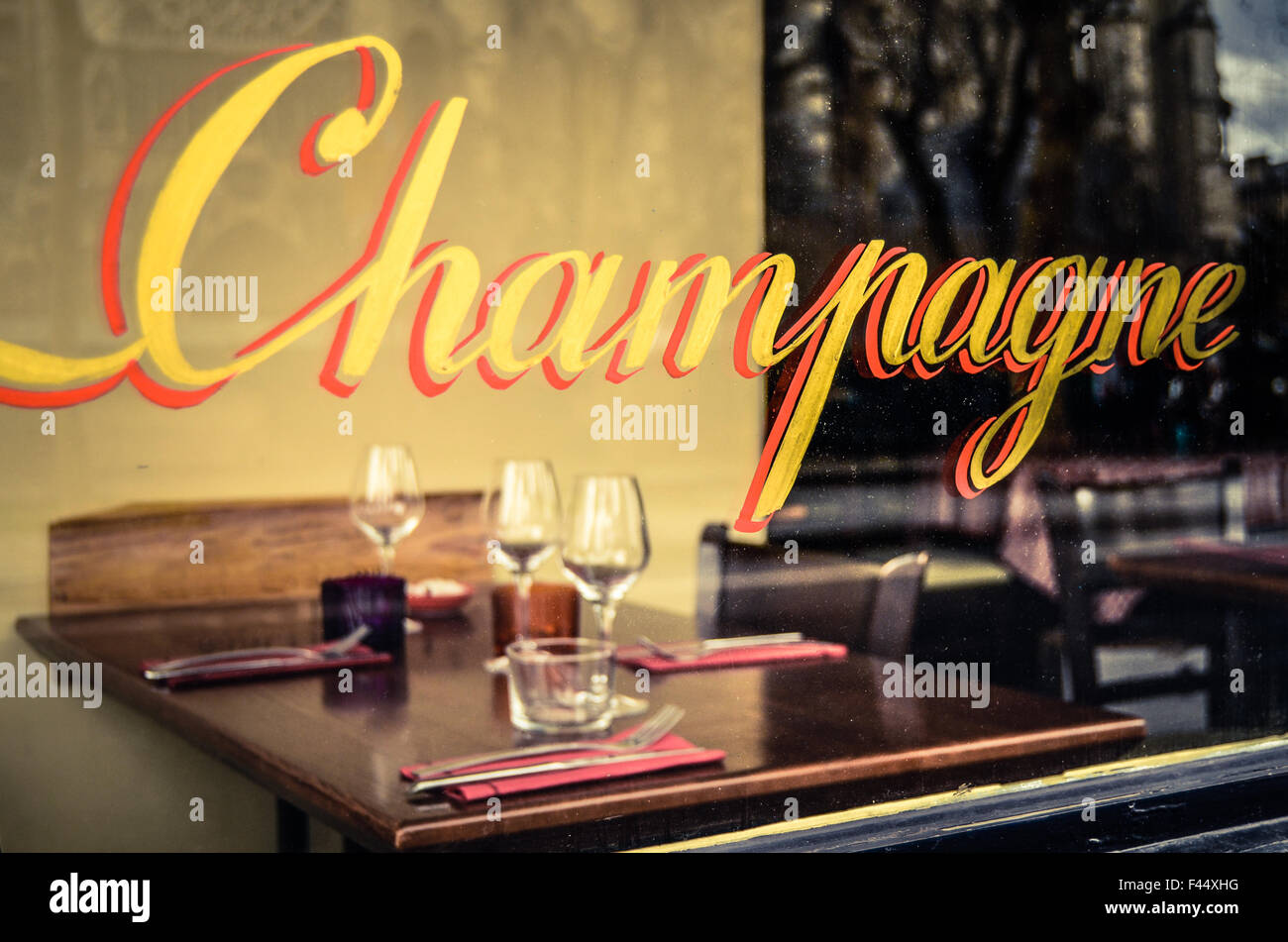 Restaurant Paris signe avec Champagne dans la fenêtre avec les couverts et verres à vin Banque D'Images