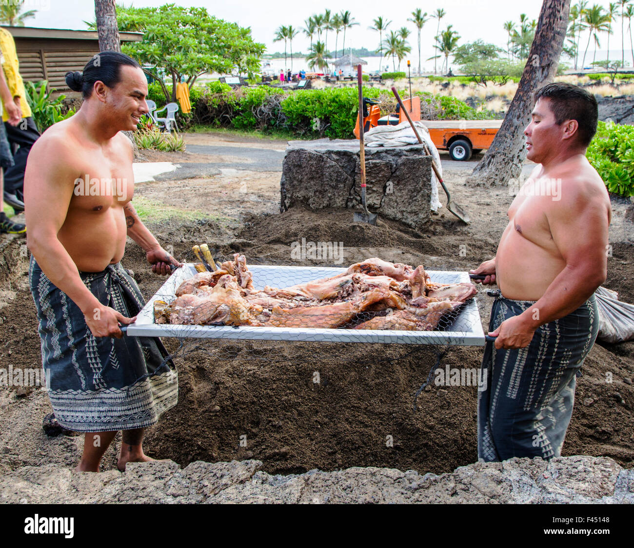 Les touristes à Lau watch autochtones préparer un cochon entier cuit dans une fosse remplie de roches chaudes, Grande Île d'Hawai'i Hawai'i ; USA ; Banque D'Images