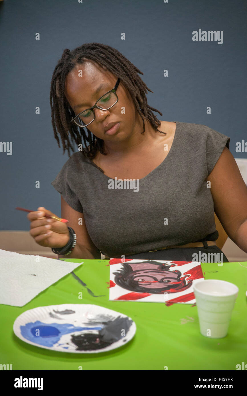 Un Afican American teen girl peint un autoportrait d'elle-même à un âge plus avancé dans un Anaheim, CA, la classe d'art où les élèves sont invités à imaginer eux-mêmes dans l'avenir. Banque D'Images