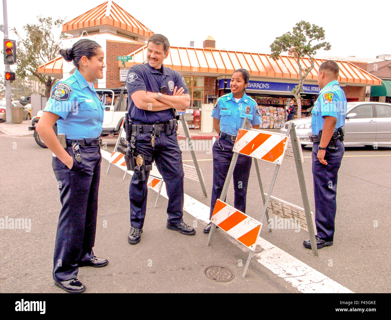 Trois jeunes adultes hispaniques auxiliaire de police sont accueillis par un policier en service à la fin de semaine une Laguna Beach, CA, intersect Banque D'Images