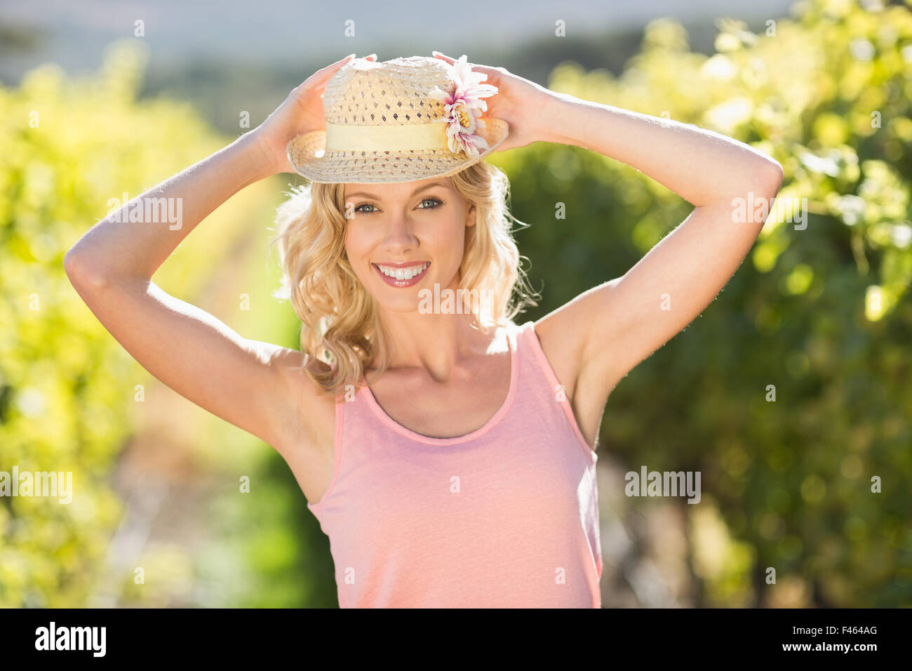 Portrait of smiling woman wearing straw hat en face de grapevine Banque D'Images