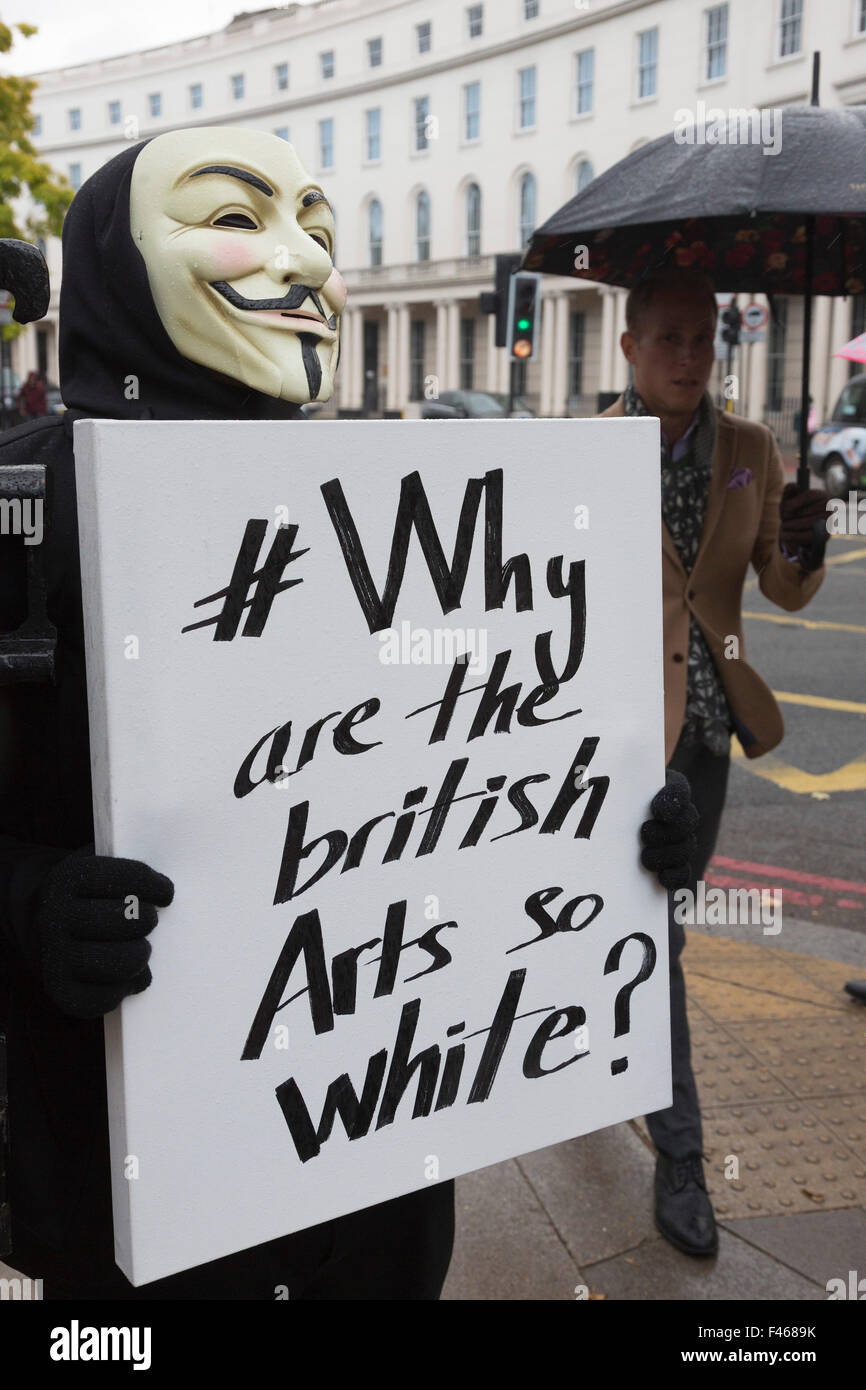 Londres, Royaume-Uni. Le 14/10/2015. Une personne portant un masque V pour Vendetta manifestations contre le racisme en arts à l'extérieur de la Frieze Art Fair à Londres en tenant une pancarte disant pourquoi les British Arts si blanche ? Credit : Nick Savage/Alamy Live News Banque D'Images
