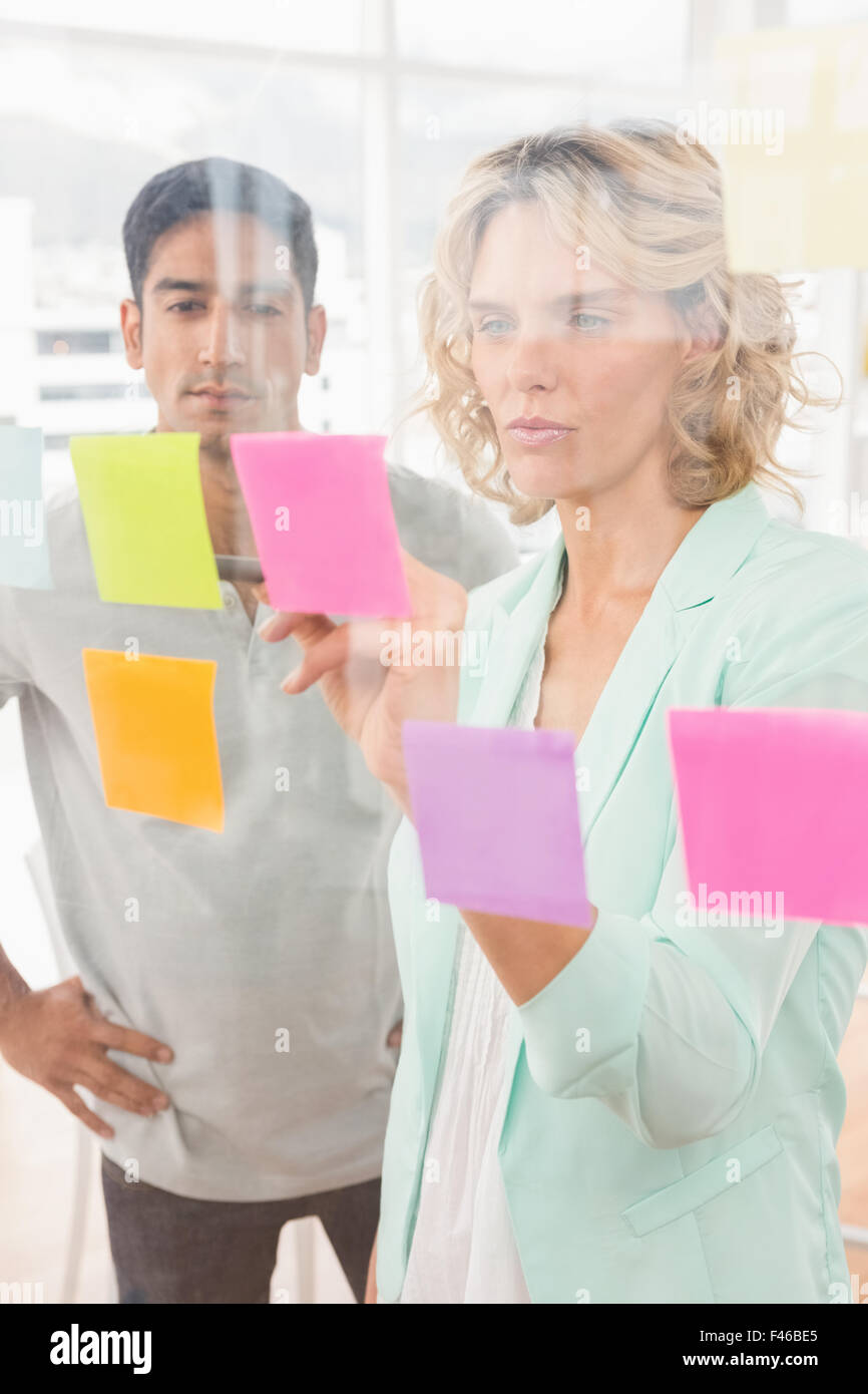 Young businesspeople pointing at sticky notes Banque D'Images Young businesspeople pointing at sticky notes Banque D'Images