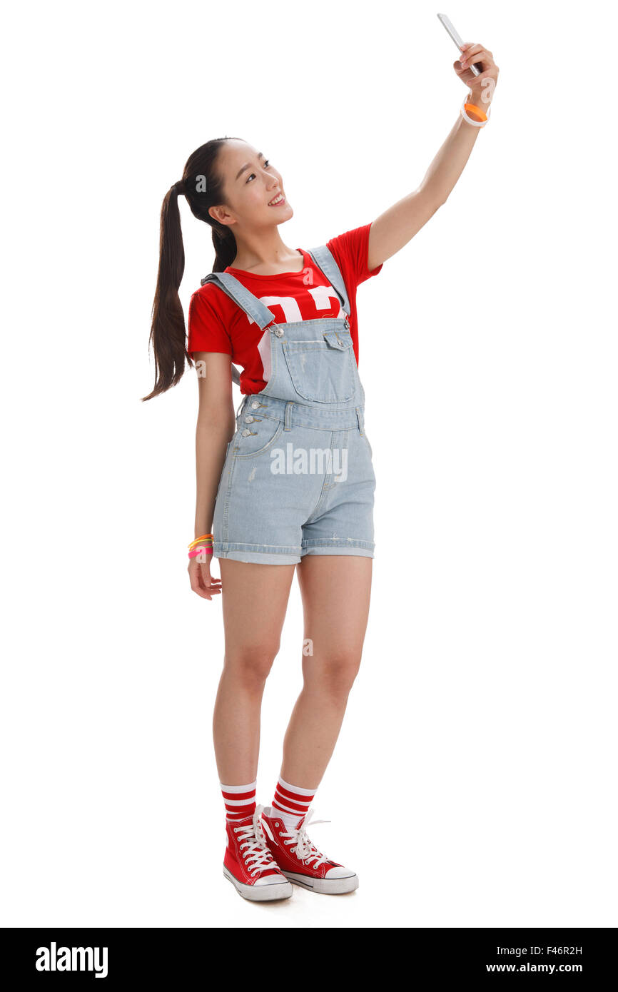 Jeune femme de prendre une photo d'elle-même avec un téléphone mobile Banque D'Images