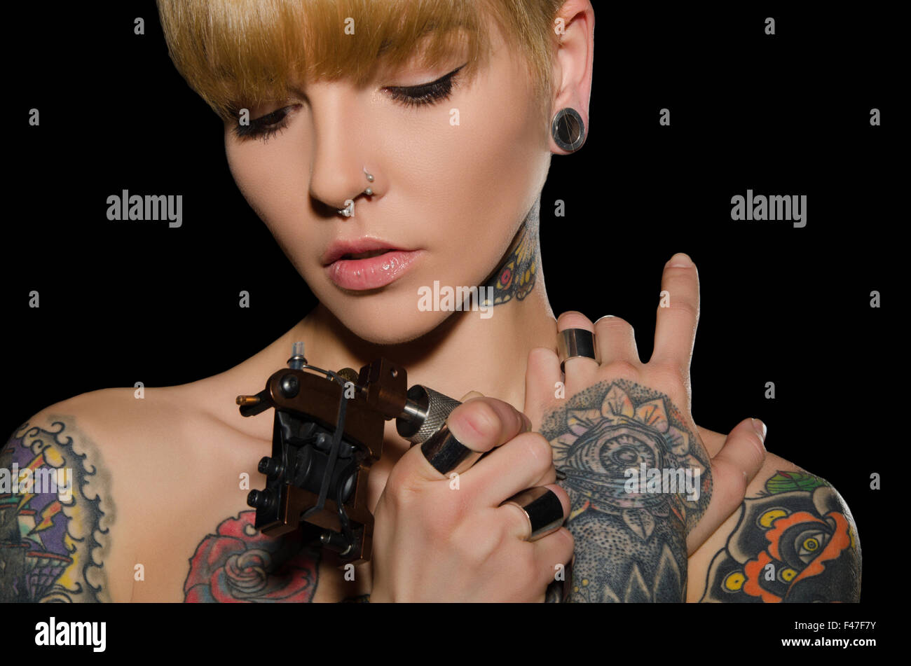 Jeune femme tatouée avec machine à tatouer Banque D'Images