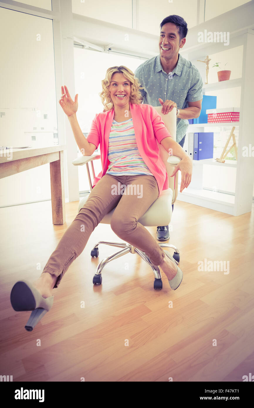 Smiling collègues jouer ensemble avec fauteuil pivotant Banque D'Images Smiling collègues jouer ensemble avec fauteuil pivotant Banque D'Images