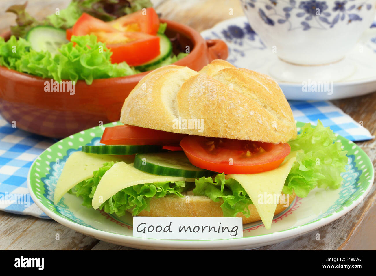 Bonjour carte avec petit-déjeuner composé de rouleau de fromage, salade verte et une tasse de thé Banque D'Images