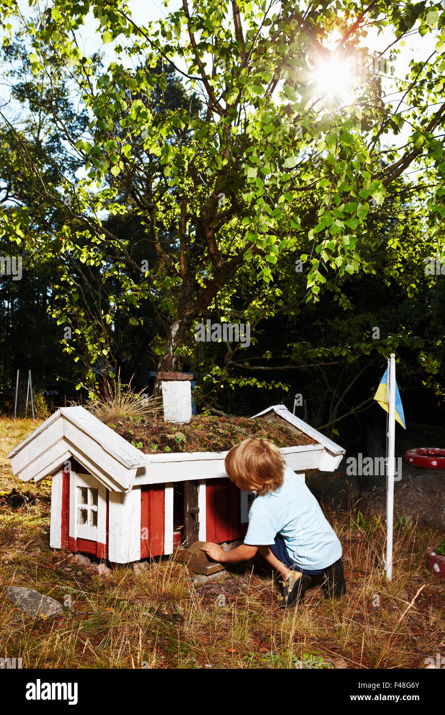 Garçon par une maison miniature, en Suède. Banque D'Images