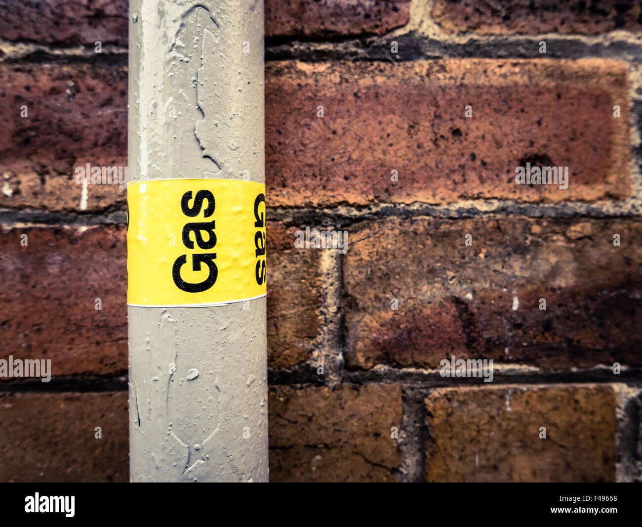 Détail d'un tuyau de gaz résidentiel contre un mur de brique rouge Banque D'Images
