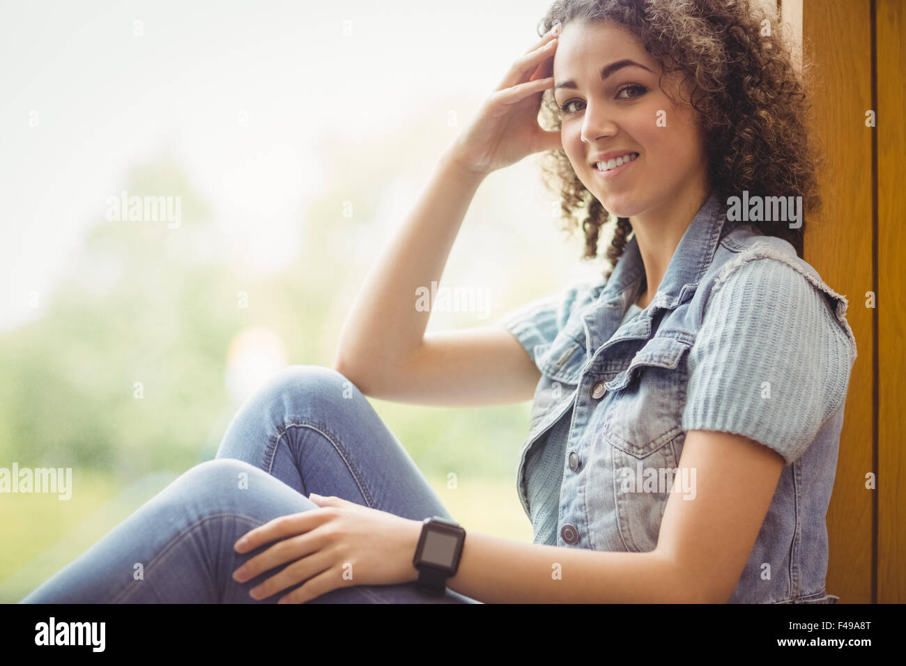 Pretty student sitting by window smiling at camera Banque D'Images