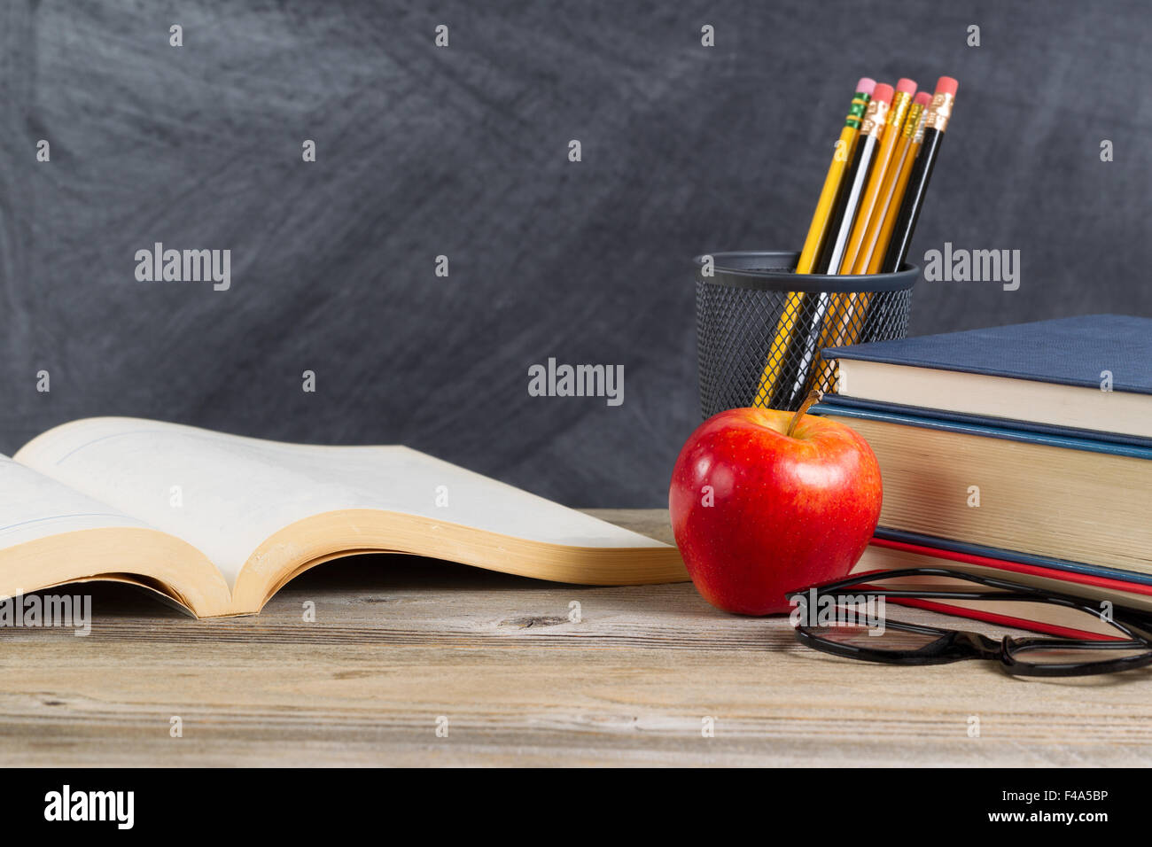 Bureau avec books, pomme rouge, lunettes de lecture, et des crayons en face du tableau noir. La mise en page en format horizontal avec beaucoup de c Banque D'Images