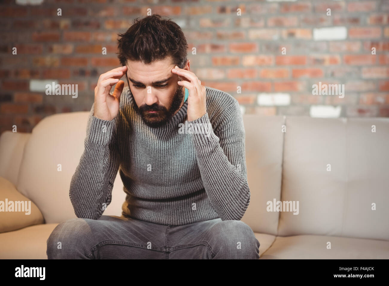 Souligné man sitting on sofa Banque D'Images