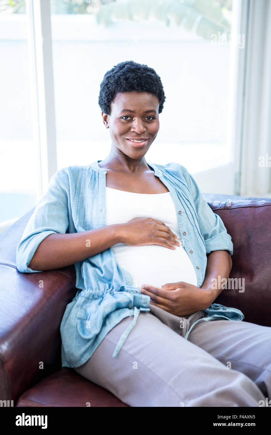 Smiling pregnant woman sitting on the couch Banque D'Images