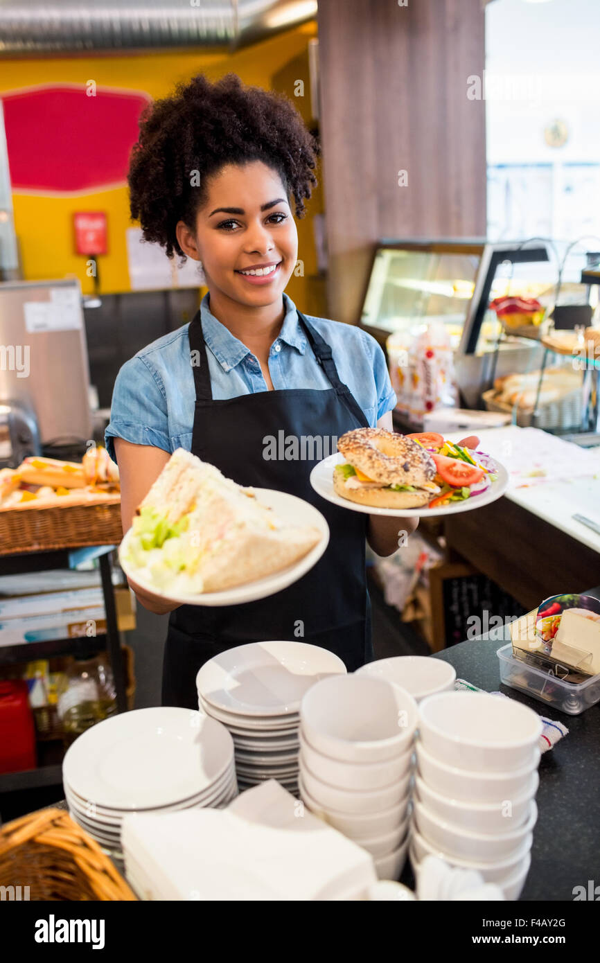 Jolie serveuse servant le déjeuner à l'appareil photo Banque D'Images