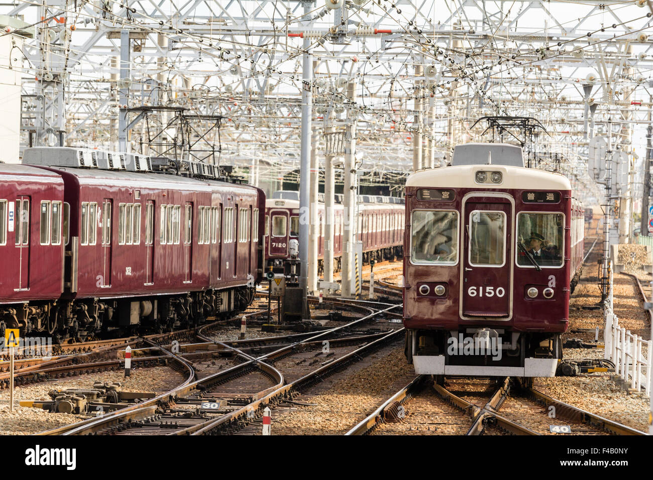 Le Japon. Vue le long labyrinthe de voies de chemin de fer et d'une couleur marron slidings Hankyu Nishinomiya privé train approchant, le jour, la lumière du soleil. Banque D'Images