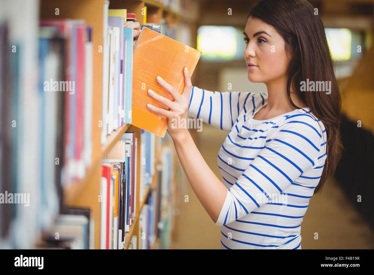 Female student choosing book Banque D'Images