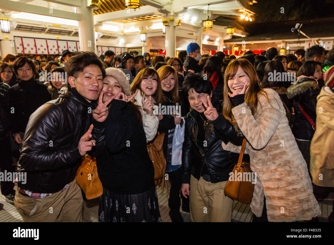 Le Japon, sanctuaire Shinto Nishinomiya, nouvel an, à minuit. Groupe de personnes en face de viewer de sourire et de donner la paix à deux doigts typique de geste. Banque D'Images