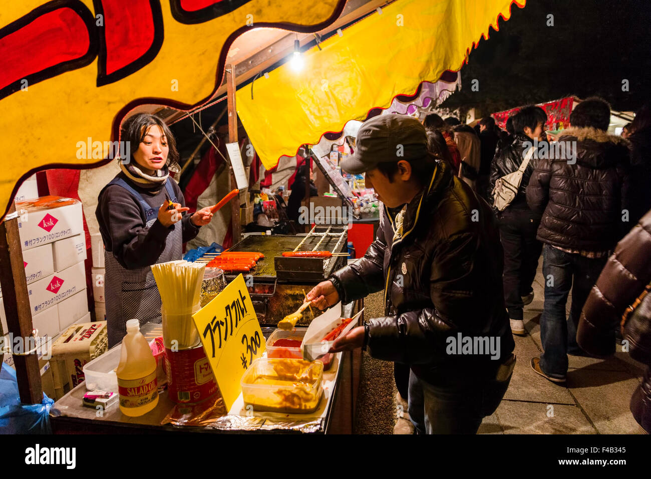 New Year's Eve, Nishinomiya culte, minuit. Food Festival typique de la vente de saucisses chaudes avec l'homme le choix de sauces pour saucisses enveloppées qu'il détient. Banque D'Images