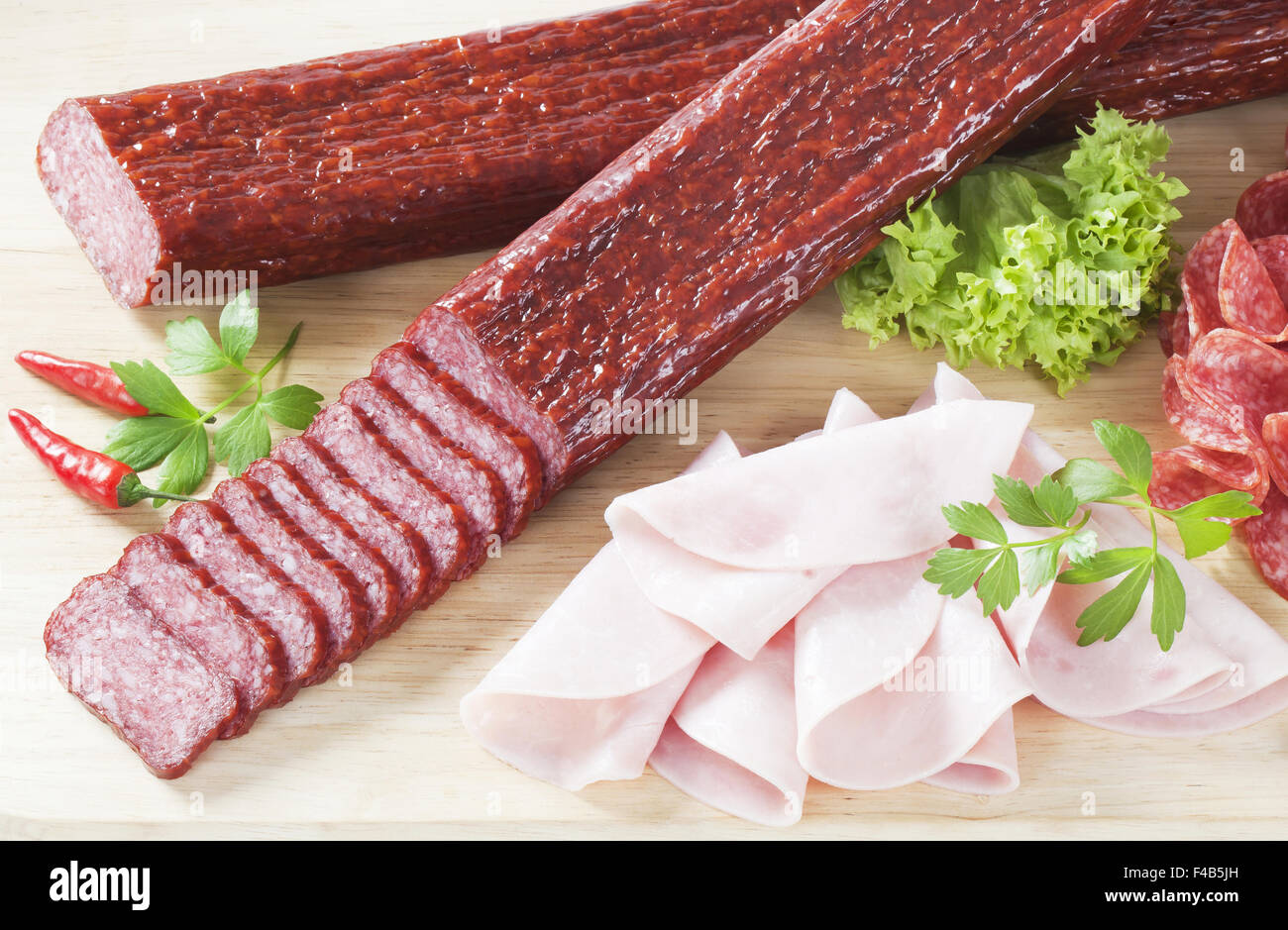 Tranches de salami et de jambon sur une planche à découper en bois Banque D'Images Tranches de salami et de jambon sur une planche à découper en bois Banque D'Images