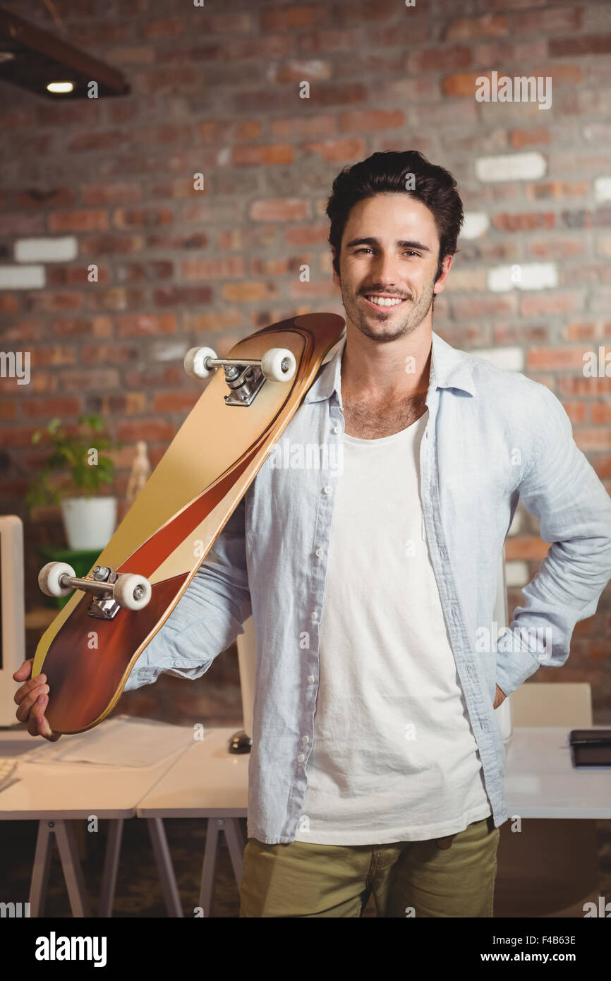 Young man carrying skateboard at office Banque D'Images