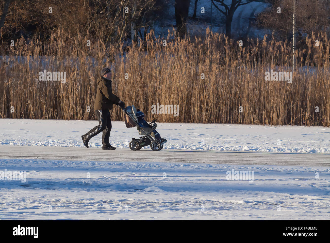 Homme avec une poussette à lac gelé. Banque D'Images