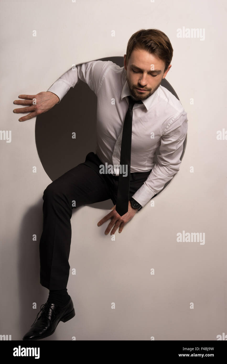 Businessman climbing out d'un trou circulaire Banque D'Images