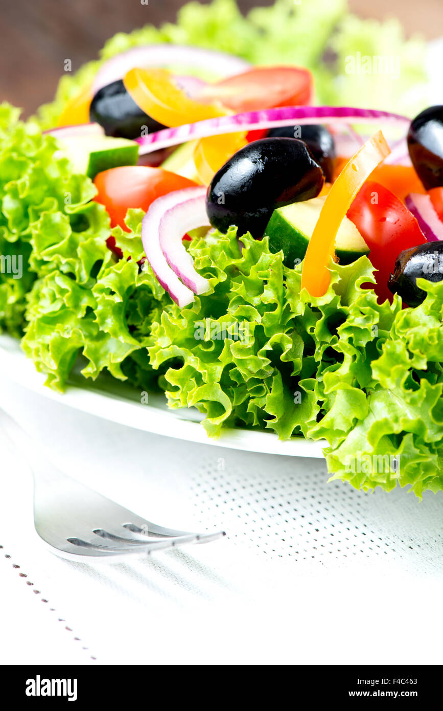 Salade avec des légumes verts et dans la plaque sur le tapis de table avec fourchette close up Banque D'Images