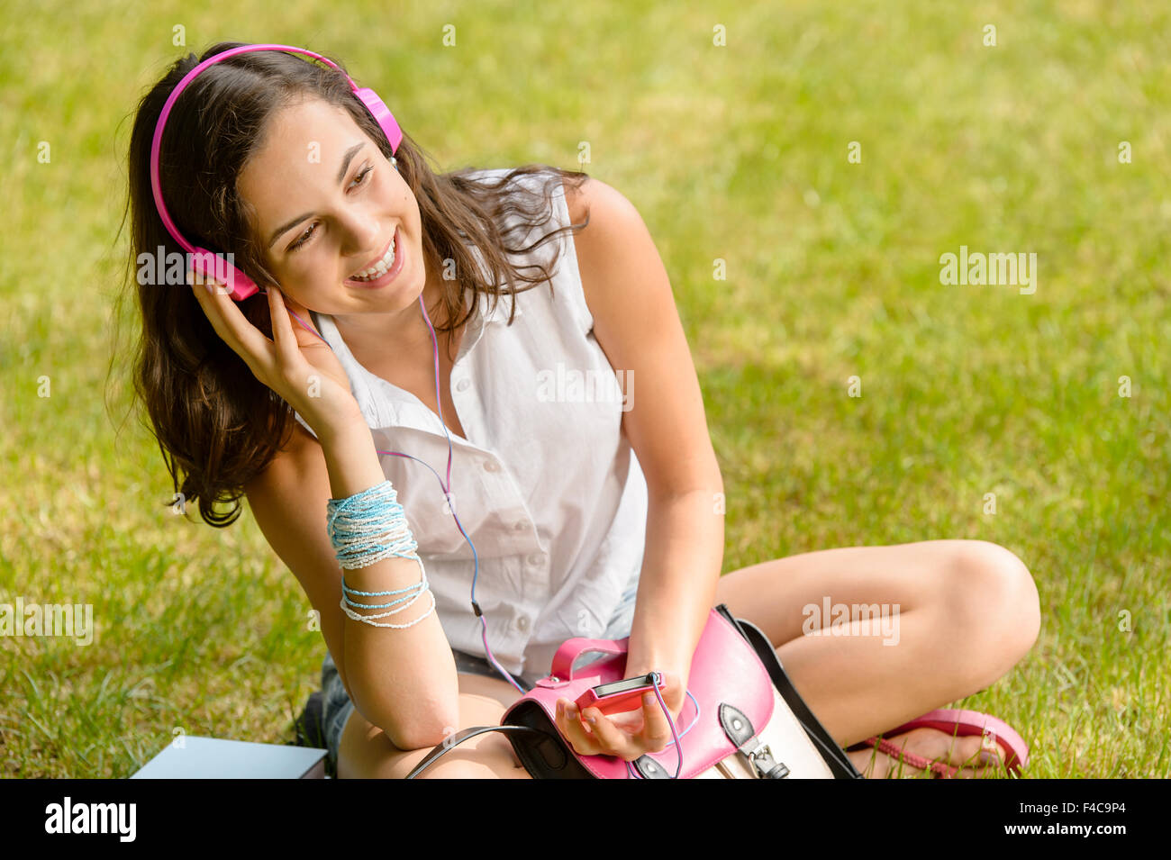 Fille d'été pour étudiants écouter de la musique assis grass Banque D'Images